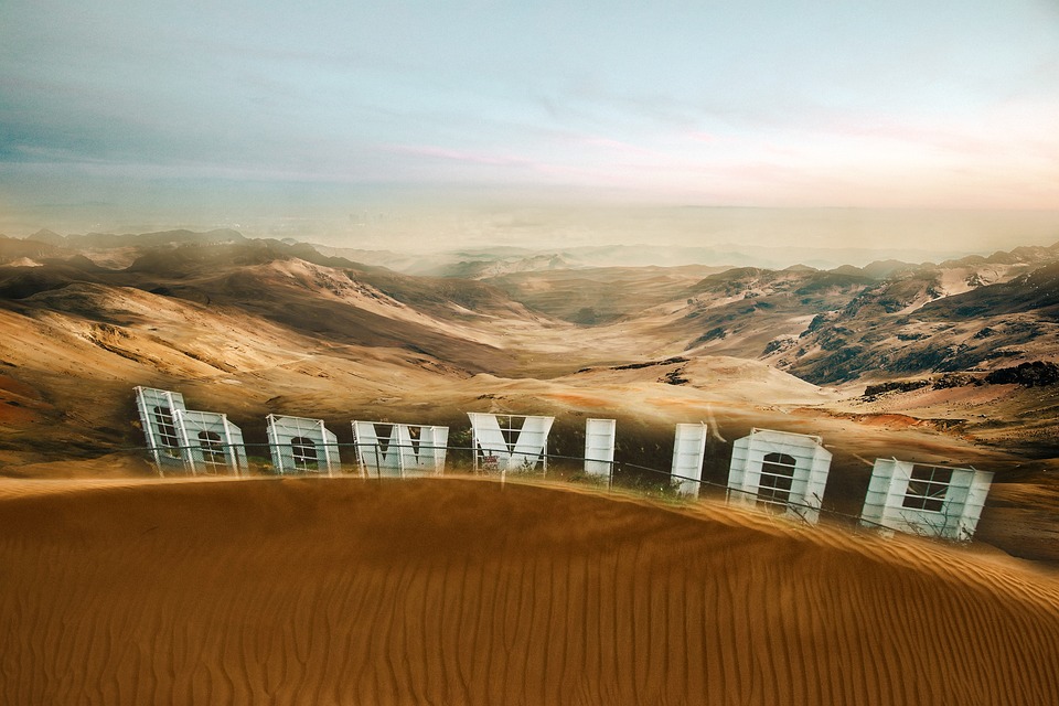 A futuristic building embedded in a desert landscape with rolling dunes and rocky mountains in the background, designed to withstand the harsh desert climate.