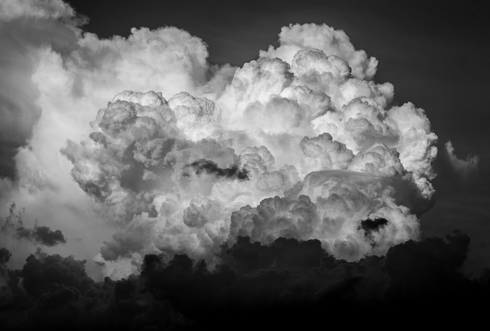 Monochrome image of billowing cumulus clouds against a dark sky, evoking thoughts about the climate.