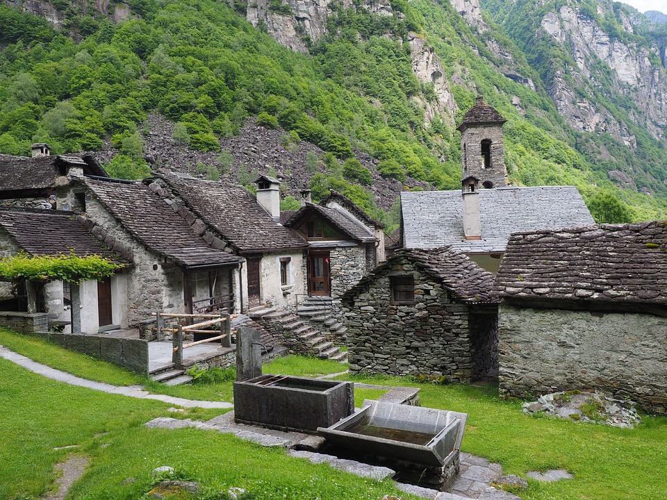 Traditional stone houses with slate roofs in a verdant mountain valley, showcasing a climate-adapted architecture.