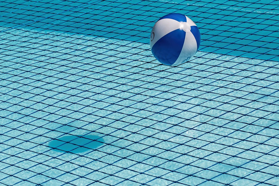 A beach ball floating in a climate-controlled swimming pool with blue tiles.