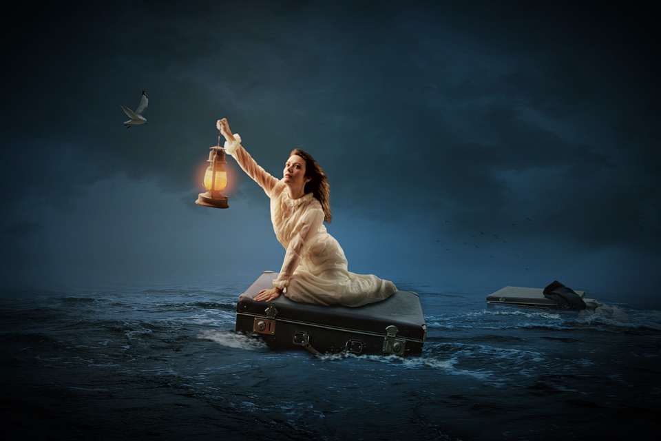 A woman holding a lantern while sitting on a floating suitcase in a dark, stormy sea, with the tumultuous climate intensifying the waves around her.